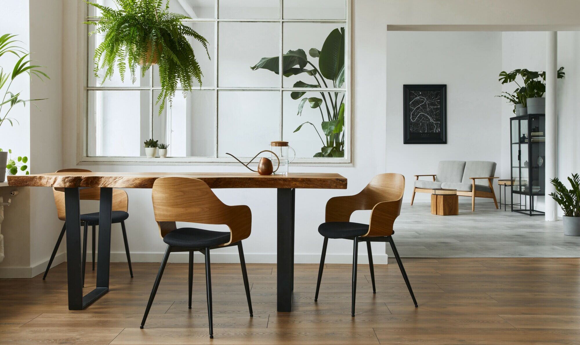 A photograph of a living room with a set of wooden and metal dining table and chairs to the left hand side with wooden flooring and a living room background