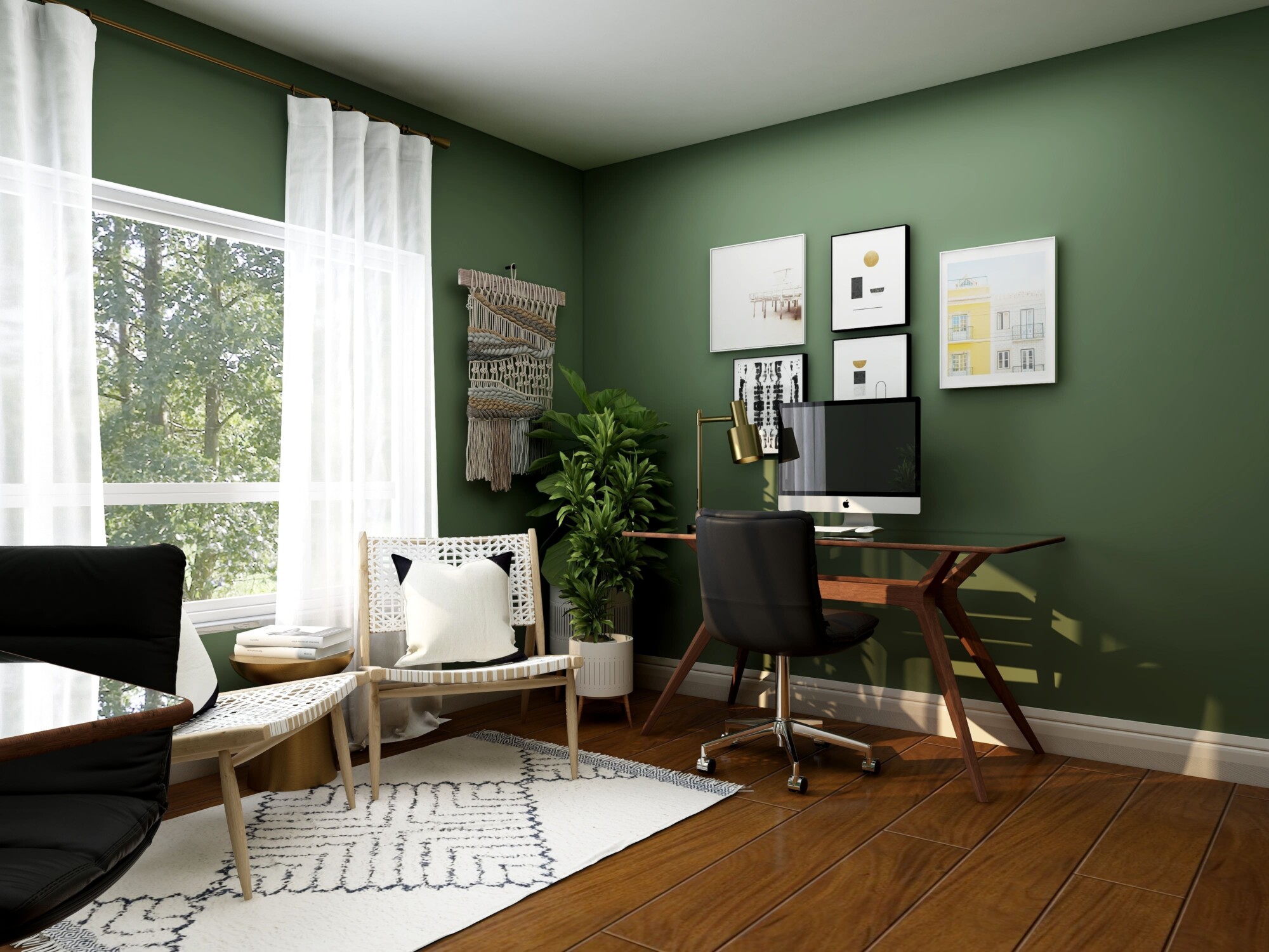 A home office with green walls, paintings above the desk computer and wooden flooring around